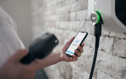 A person starting a charge with their mobile phone next to an EVBox Elvi home charging station